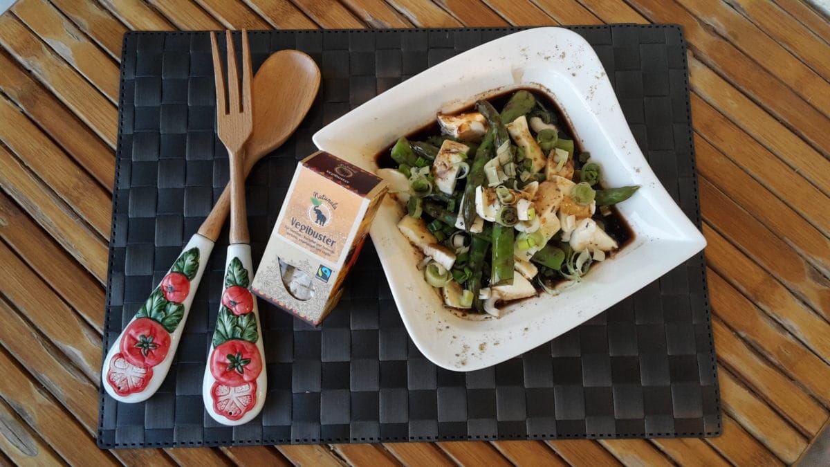 Grüner Spargelsalat mit Mozzarella auf einem Teller angerichtet mit Holzbesteck