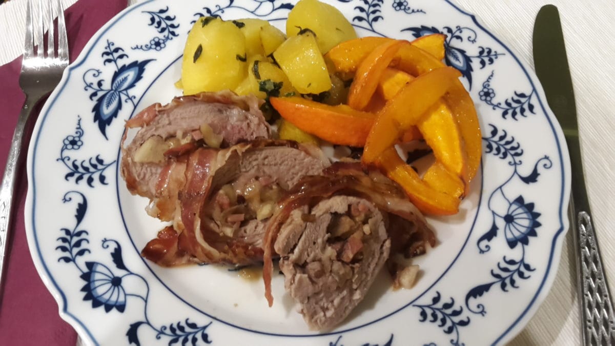 Mit Kastanien gefülltes Schweinsfilet mit Kürbisspalten und Kartoffeln auf einem Teller