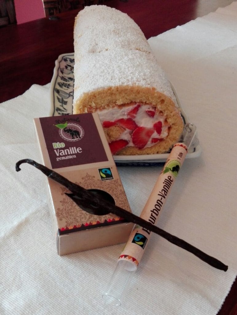 Vanillebiscuit mit Erdbeerfüllung auf einem Teller mit einer Packung Naturala Vanille gemahlen und einer Bourbon-Vanilleschote von Naturala